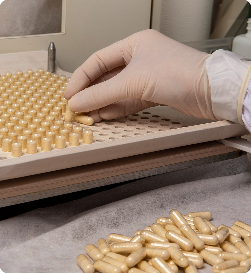 Farmacêutico manipulando cápsulas em encapsuladora na farmácia de manipulação BioAurea