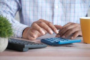 Mãos usando calculadora sobre uma mesa de trabalho, representando o cálculo do orçamento